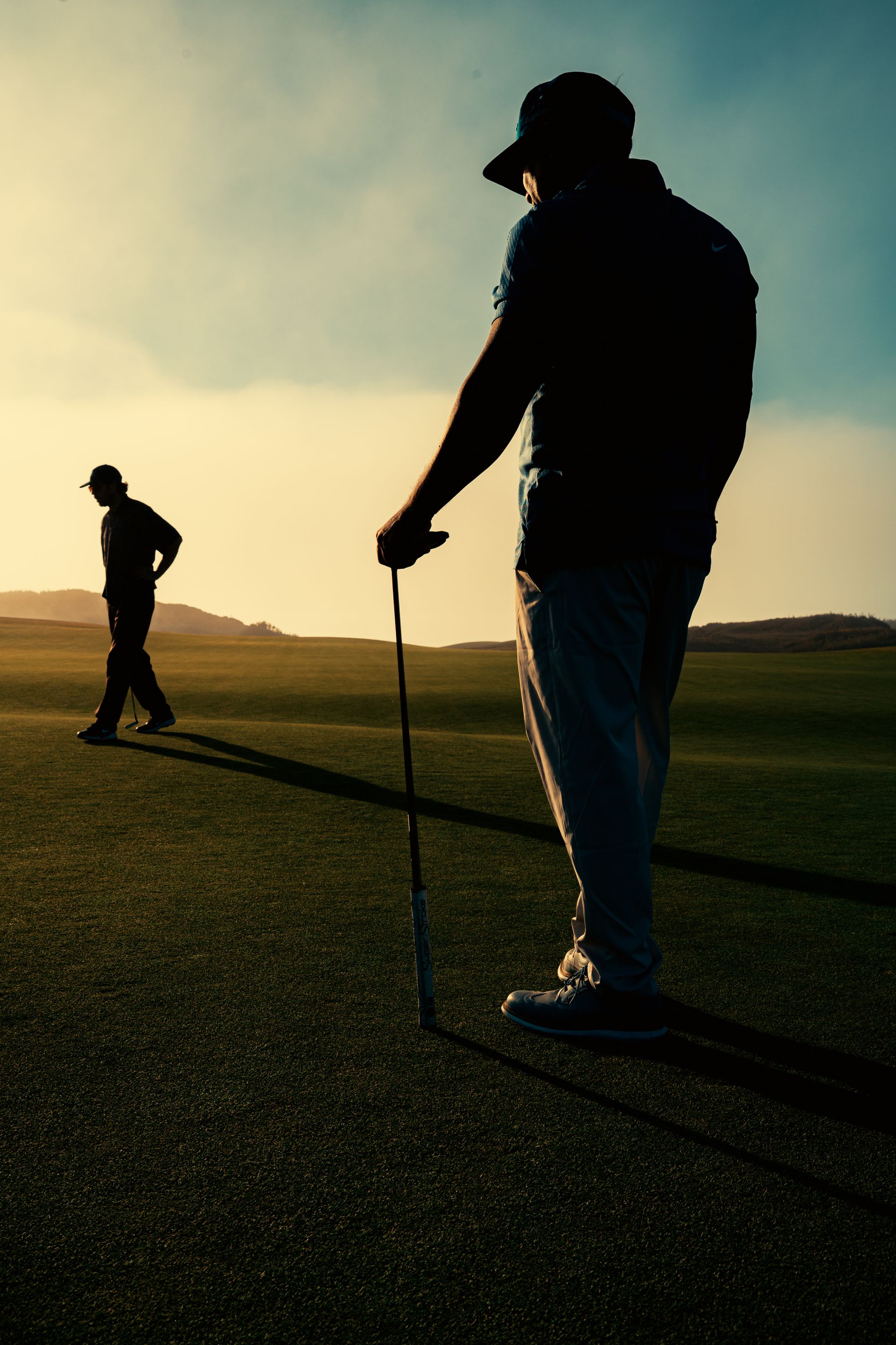 Two golfers crossing a sunlit course